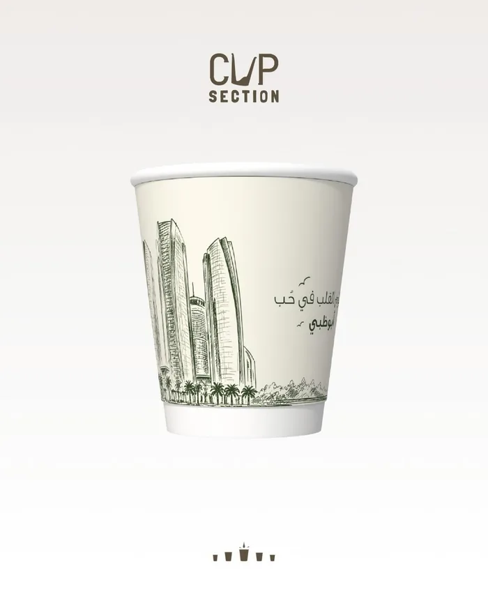 Cream paper cup with a pen sketch of Abu Dhabi towers and an Arabic line about loving Abu Dhabi.