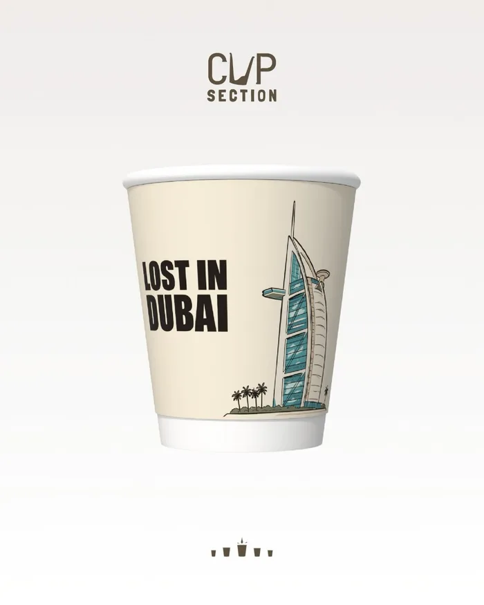 Cream paper cup reading Lost in Dubai beside a drawing of the Burj Al Arab and palm trees.