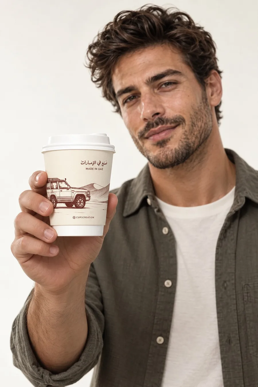 A man in an olive shirt holds out the Made in UAE 4x4 cup toward the camera.